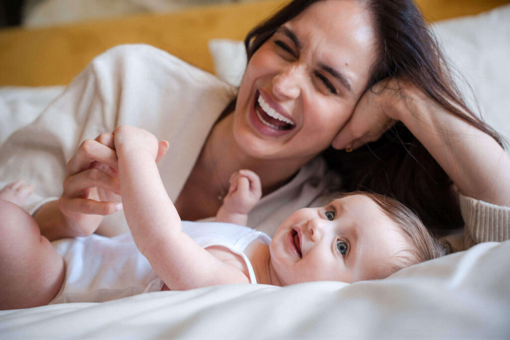 Mom and daughter cuddling together on the bed during a relaxed, in-home photography session in Munich.